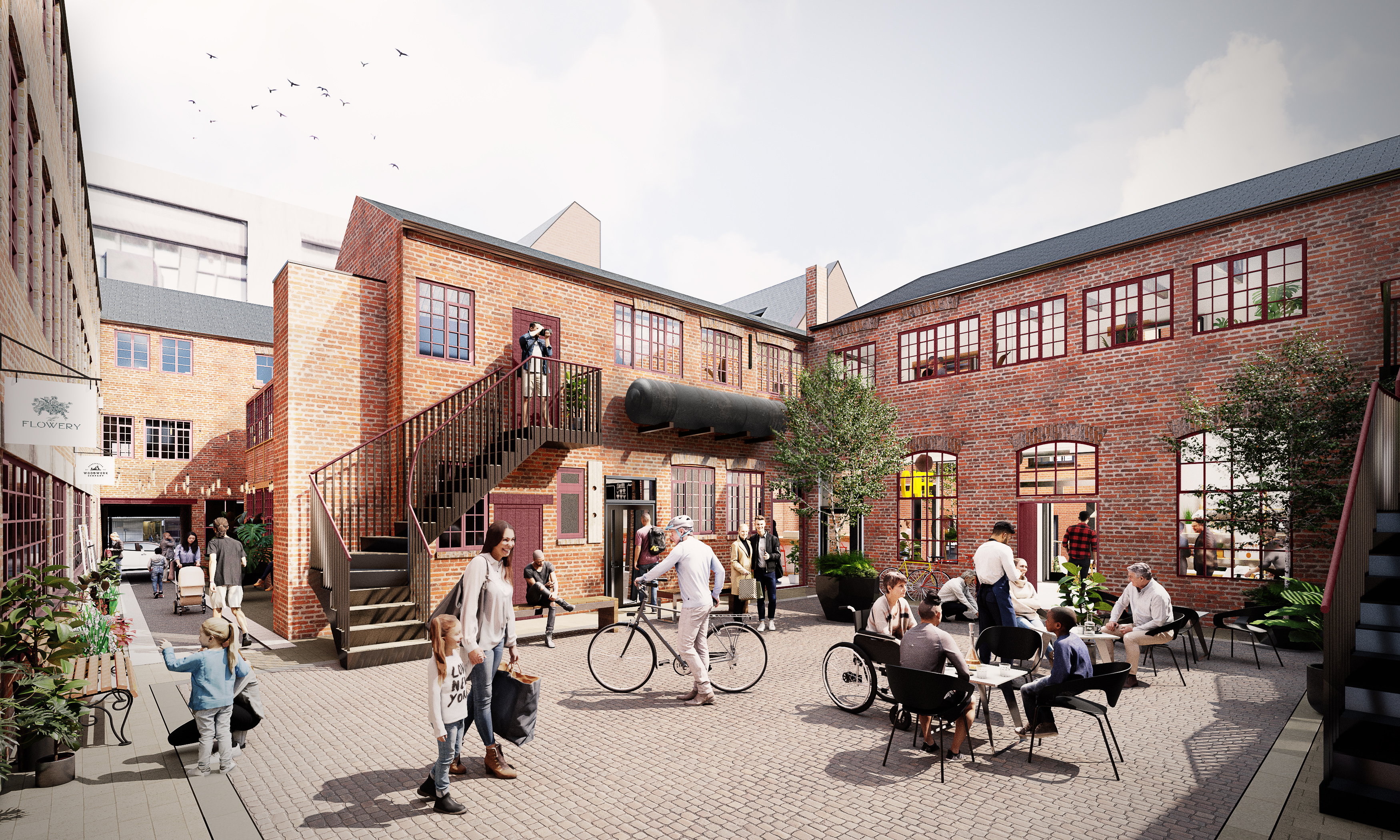 CGI-rendered courtyard scene with red-brick buildings featuring large windows and outdoor staircases. People are walking, cycling, and sitting at black tables enjoying food and drinks. There are potted trees and signage for shops, creating a lively, modern communal space.