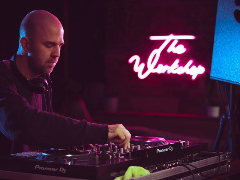 A man plays music at a DJ desk.